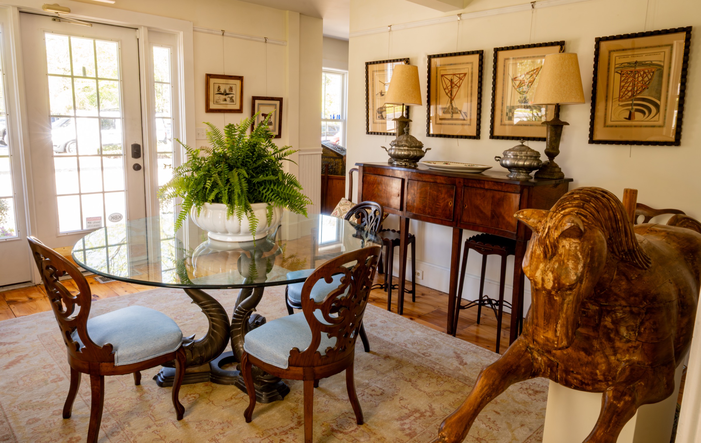 Dining table, chairs, framed art, and antique furnishings inside the shop.