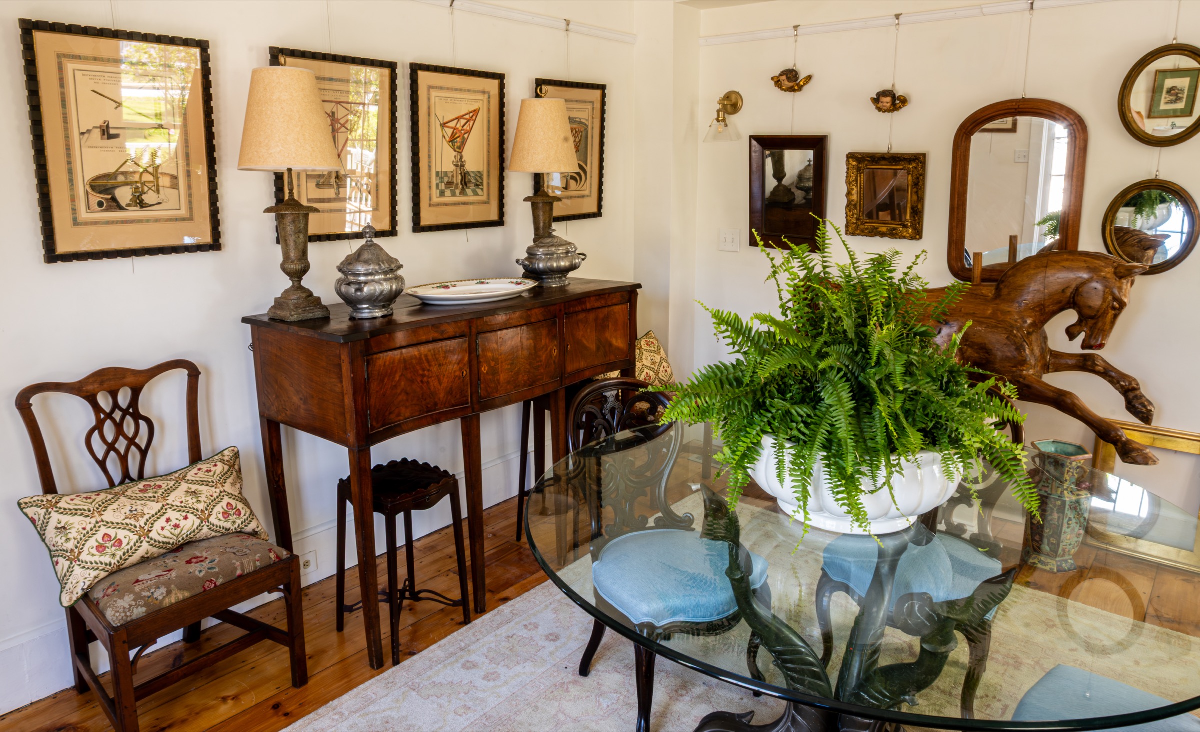 Antique furniture, mirrors, lamps, and a glass table with a fern.