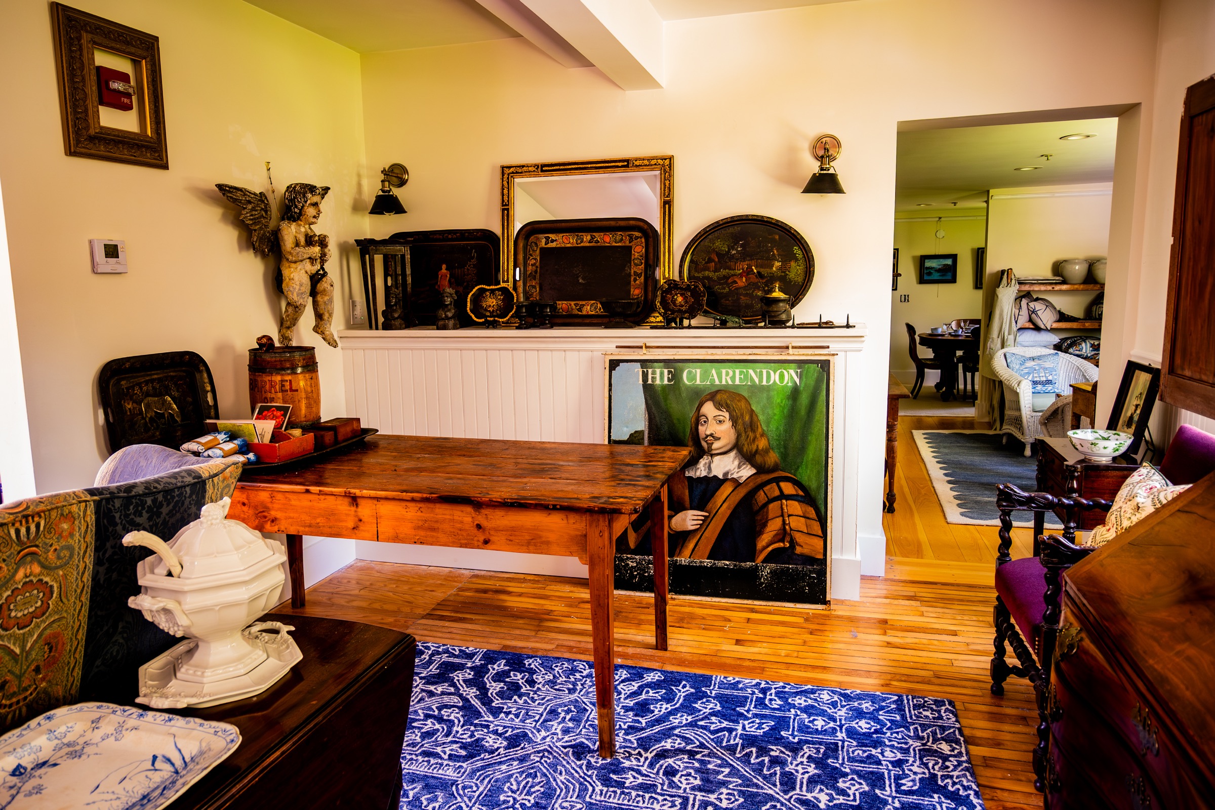 Antique table, folk art, framed trays, and chairs on display.